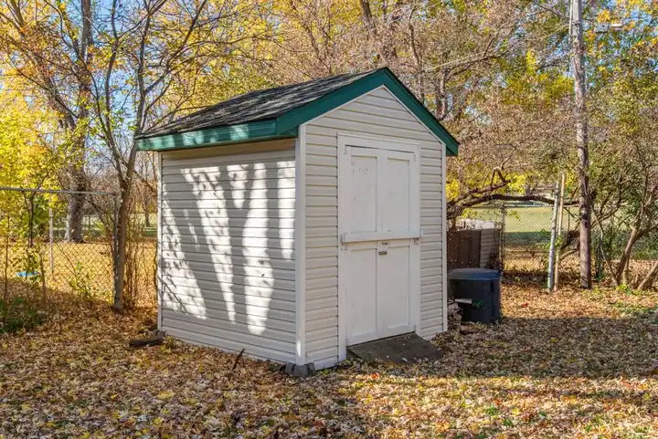 A quaint backyard shed surrounded by autumn foliage, ideal for storage solutions.