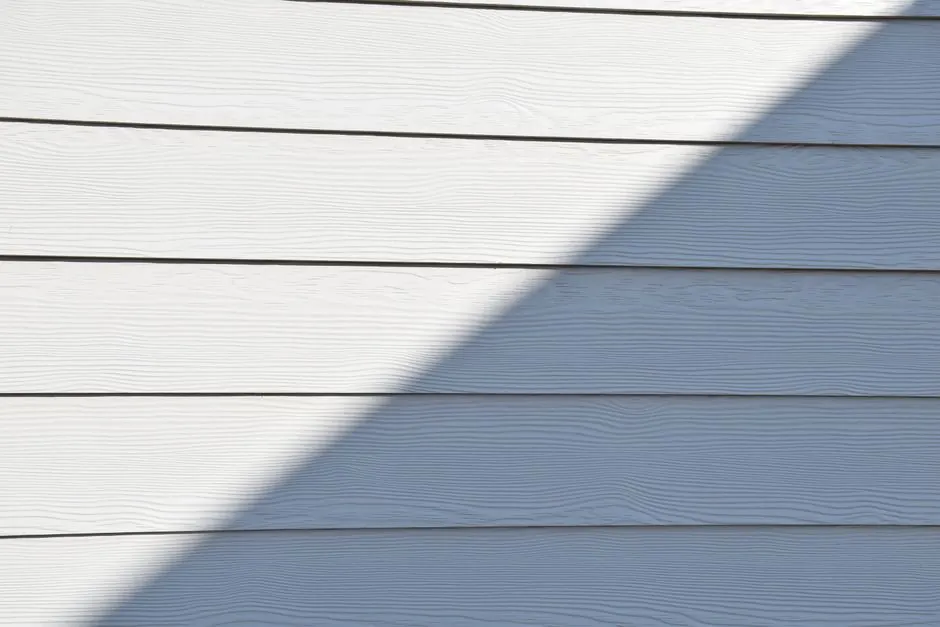 Close-up of a white wooden wall featuring a bold diagonal shadow.