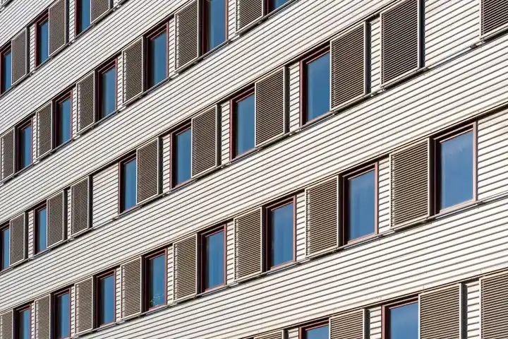 Geometric view of building facade featuring multiple windows and shutters.