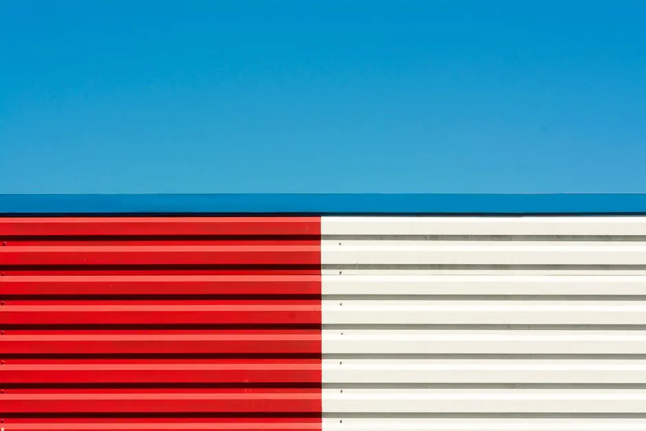 Stylish abstract image of a red and white striped wall with a vivid blue sky background, perfect for modern design projects.